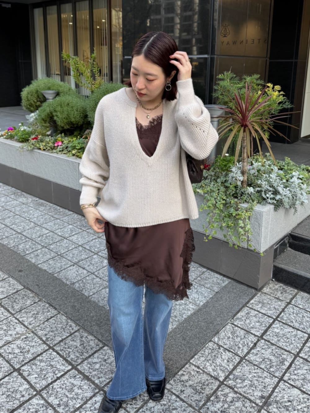 ブラウン系のキャミソール、ブルー系のデニムパンツ、ホワイト系のニット/セーターを着用したレディースの冬コーディネートの3枚目の写真