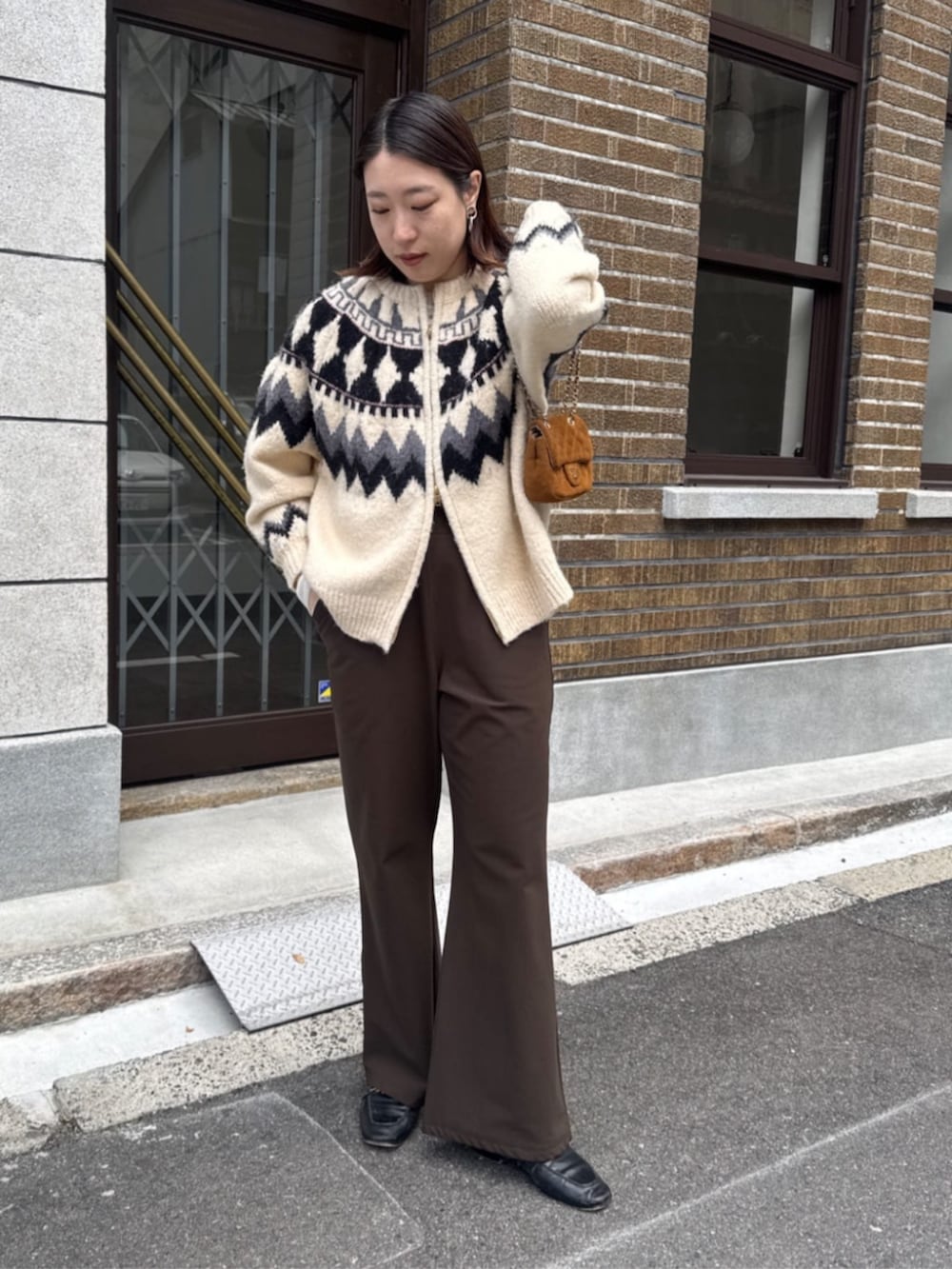 イエロー系のショルダーバッグ、ホワイト系のカーディガン/ボレロ、ブラウン系のその他パンツを着用したレディースの冬コーディネートの4枚目の写真