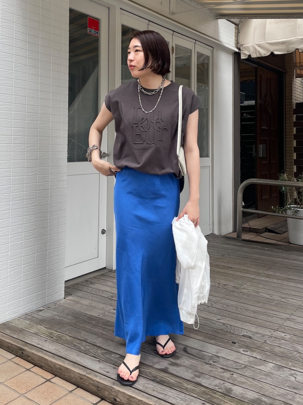 ブルー系のスカート、グレー系のTシャツ/カットソー、ホワイト系のブルゾンを着用したレディースの春コーディネートの6枚目の写真