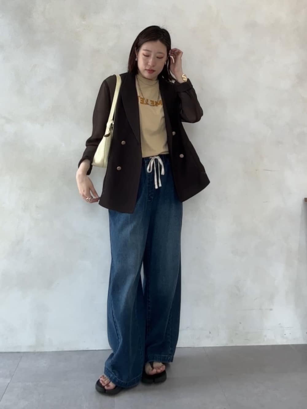 ブルー系のデニムパンツ、イエロー系のショルダーバッグ、ベージュ系のTシャツ/カットソーを着用したレディースの夏コーディネートの2枚目の写真