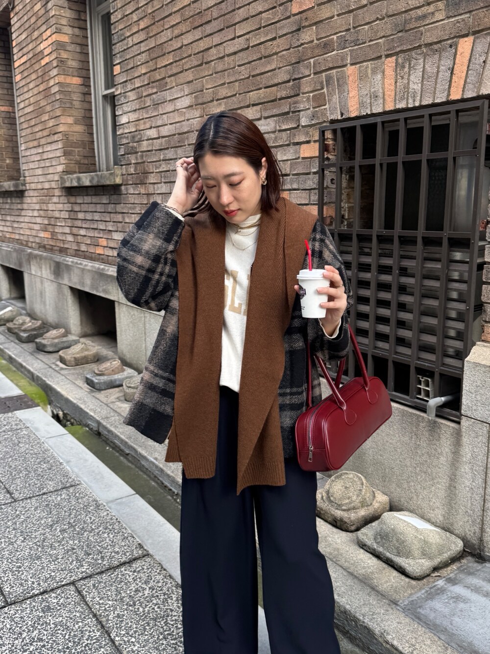 ブルー系のスラックス、ホワイト系のニット/セーター、レッド系のショルダーバッグを着用したレディースの秋コーディネートの5枚目の写真