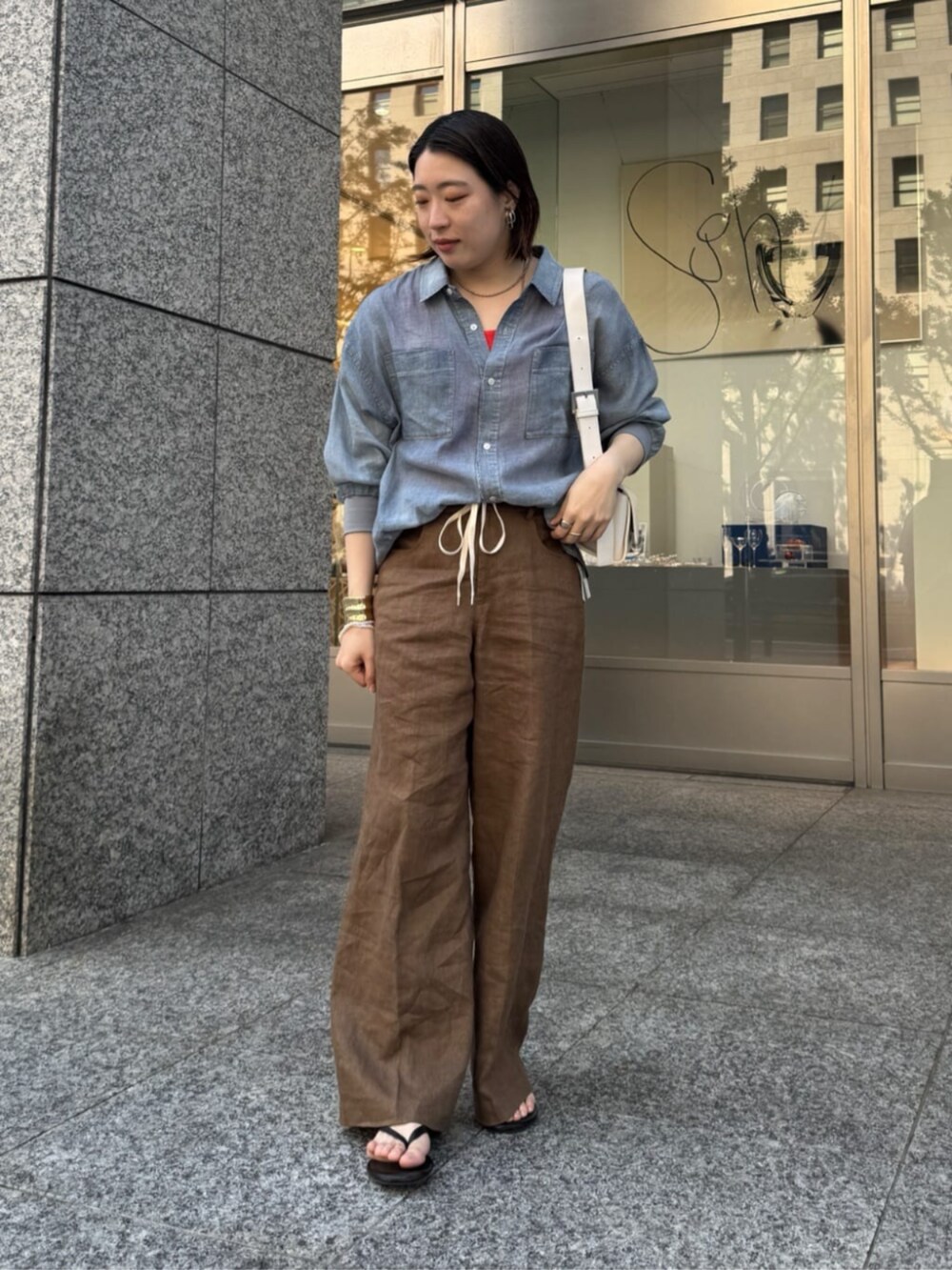 ホワイト系のショルダーバッグ、ブルー系のシャツ/ブラウス、オレンジ系のタンクトップを着用したレディースの春コーディネートの6枚目の写真