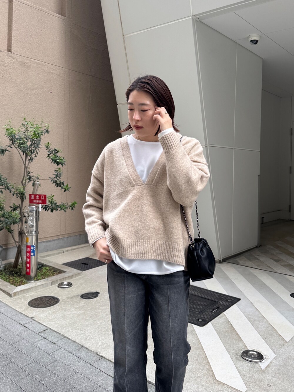 ブラック系のデニムパンツ、ベージュ系のニット/セーター、ホワイト系のTシャツ/カットソーを着用したレディースの秋コーディネートの4枚目の写真