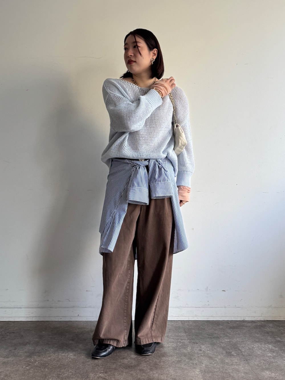 ブルー系のニット/セーター、ピンク系のTシャツ/カットソー、ブラウン系のデニムパンツを着用したレディースの冬コーディネートの2枚目の写真