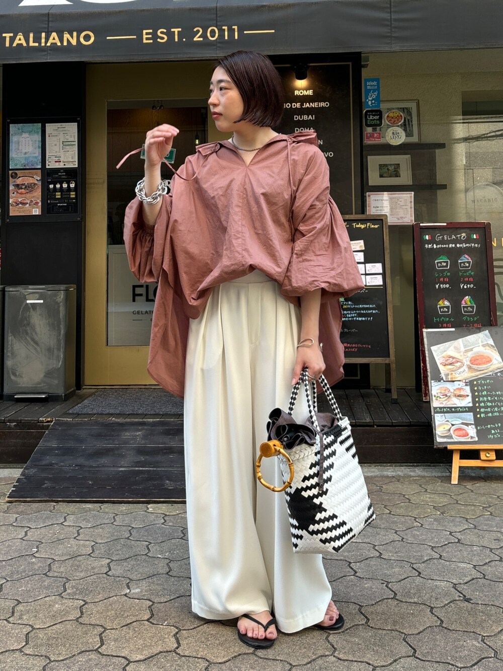 ホワイト系のスラックス、ブラウン系のシャツ/ブラウス、ホワイト系のかごバッグを着用したレディースの夏コーディネートの2枚目の写真