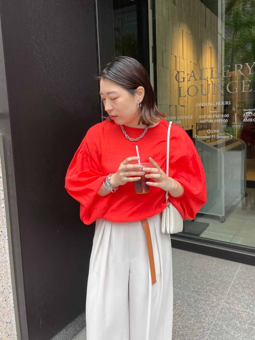 グレー系のスラックス、オレンジ系のシャツ/ブラウス、ホワイト系のショルダーバッグを着用したレディースの春コーディネートの9枚目の写真