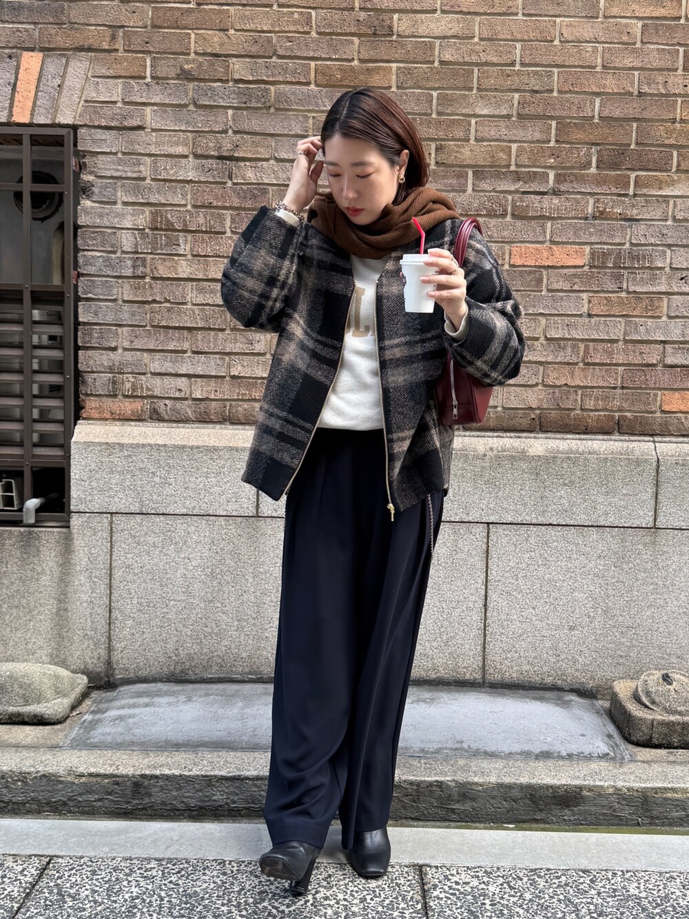 ブルー系のスラックス、ホワイト系のニット/セーター、レッド系のショルダーバッグを着用したレディースの秋コーディネートの3枚目の写真