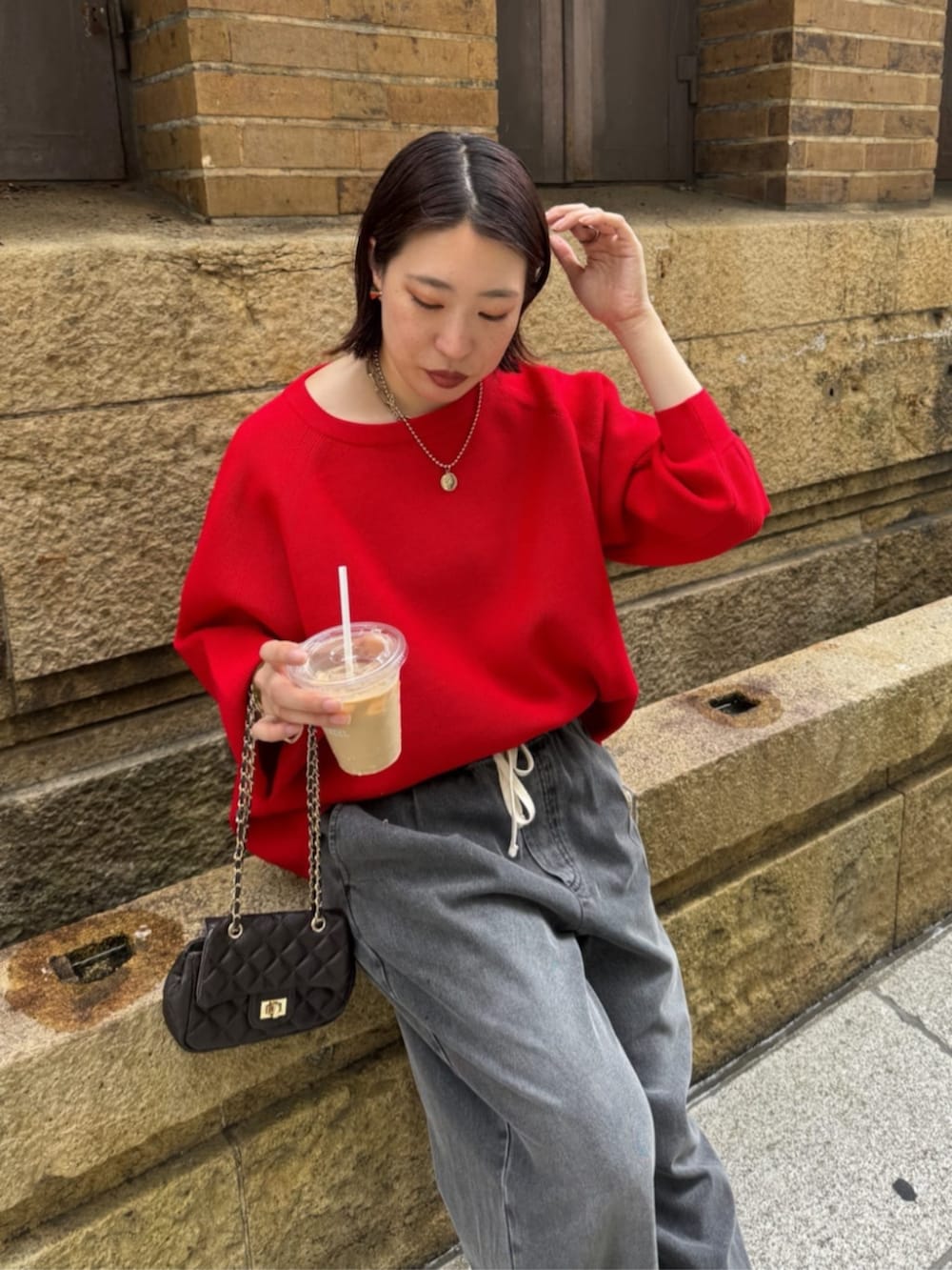 ブラック系のデニムパンツ、ブラウン系のショルダーバッグ、レッド系のニット/セーターを着用したレディースの夏コーディネートの8枚目の写真