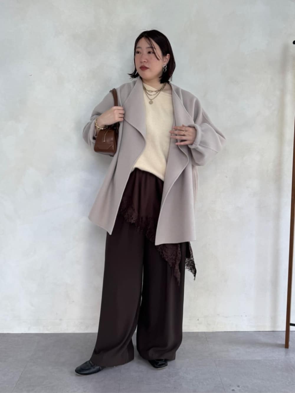 ブラウン系のスラックス、ベージュ系のその他アウター、ブラウン系のキャミソールを着用したレディースの冬コーディネートの3枚目の写真