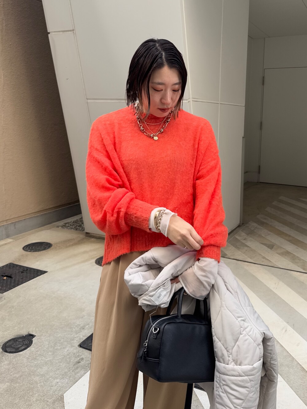 ベージュ系のその他パンツ、ホワイト系のその他アウター、オレンジ系のニット/セーターを着用したレディースの冬コーディネートの7枚目の写真