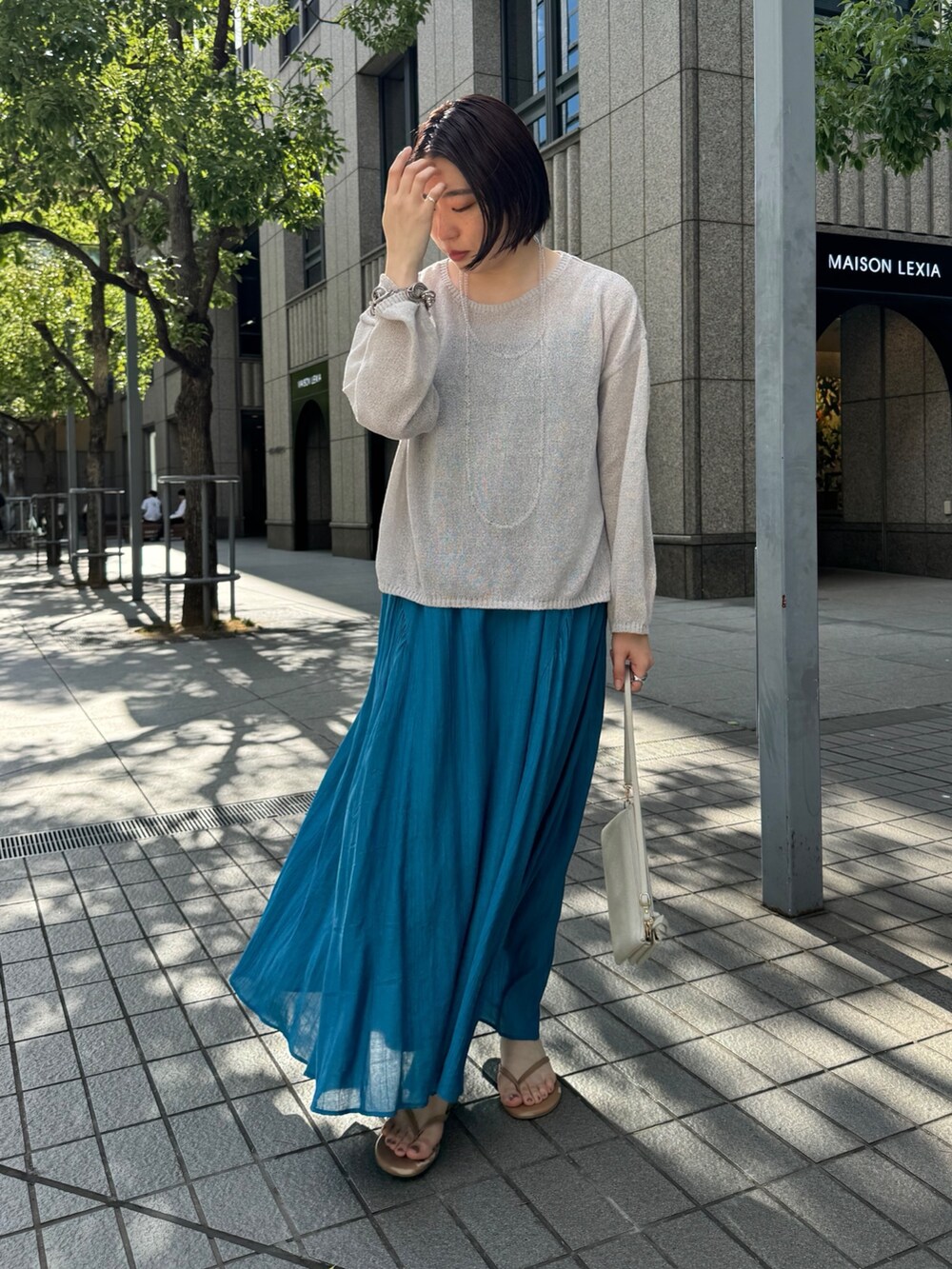 ブルー系のワンピース、ベージュ系のニット/セーター、ホワイト系のショルダーバッグを着用したレディースの夏コーディネートの2枚目の写真