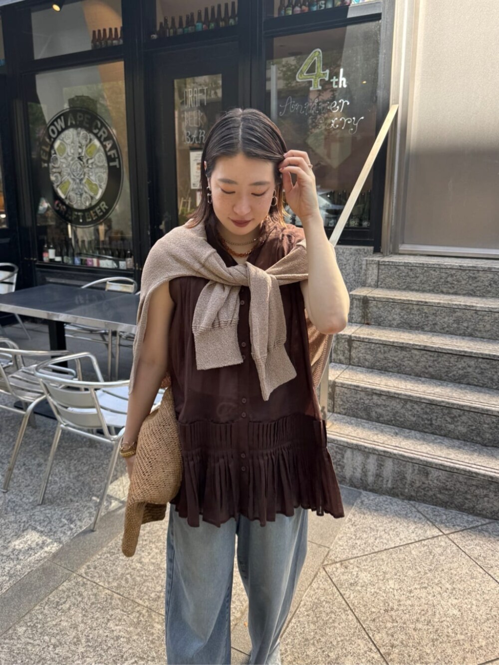 ブルー系のデニムパンツ、ベージュ系のカーディガン/ボレロ、ブラウン系のシャツ/ブラウスを着用したレディースの春コーディネートの4枚目の写真