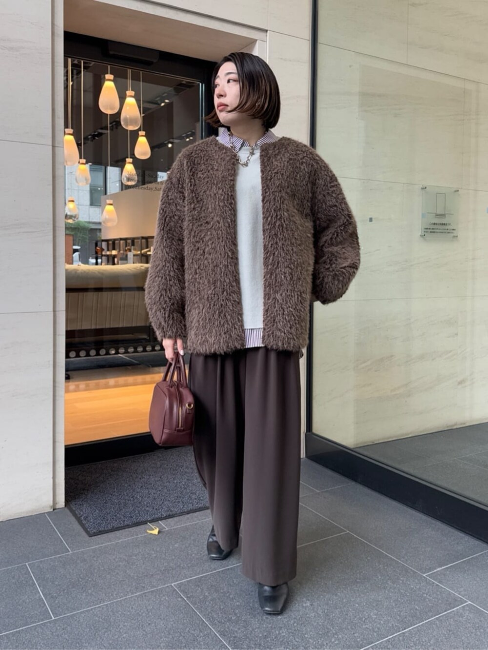 ブラウン系のスラックス、レッド系のシャツ/ブラウス、ブラウン系のショルダーバッグを着用したレディースの冬コーディネートの4枚目の写真