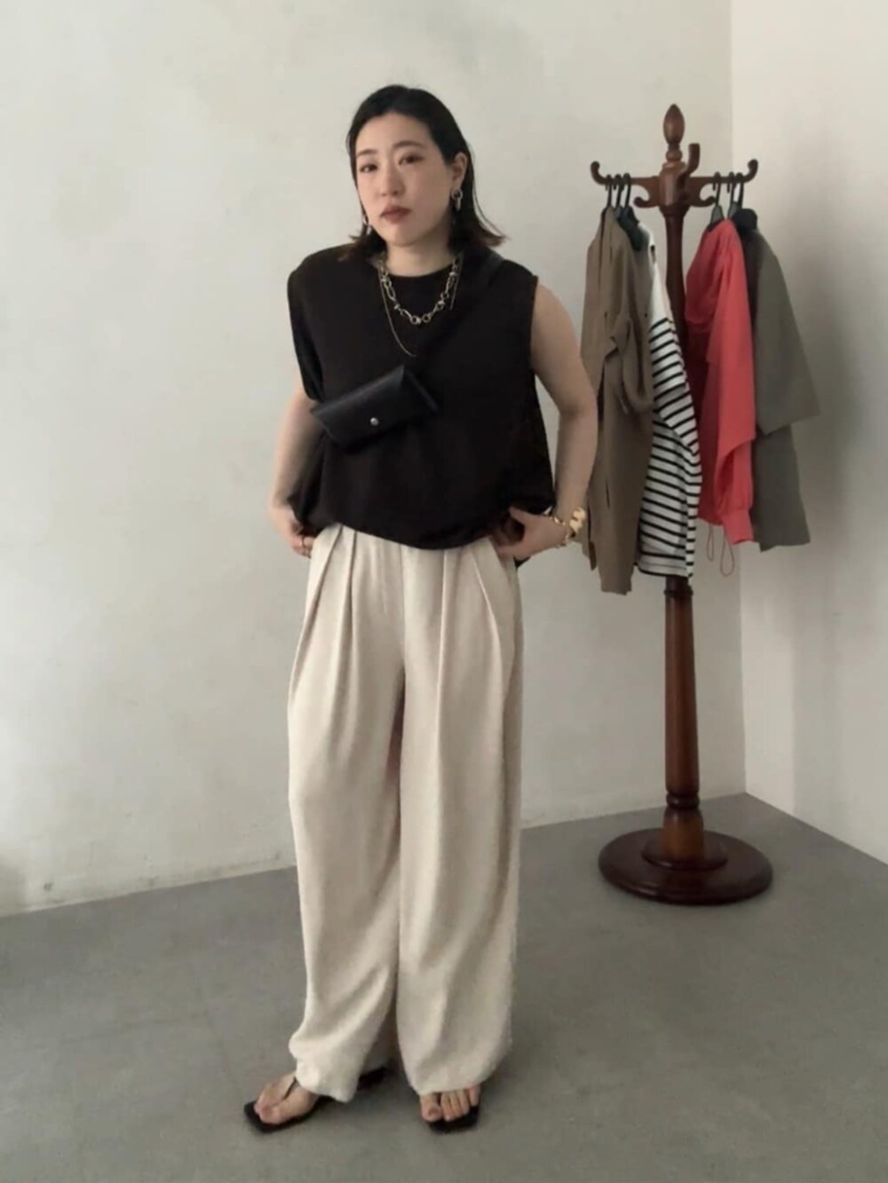 ブラウン系のショルダーバッグ、ブラウン系のTシャツ/カットソー、ベージュ系のスラックスを着用したレディースの夏コーディネートの3枚目の写真