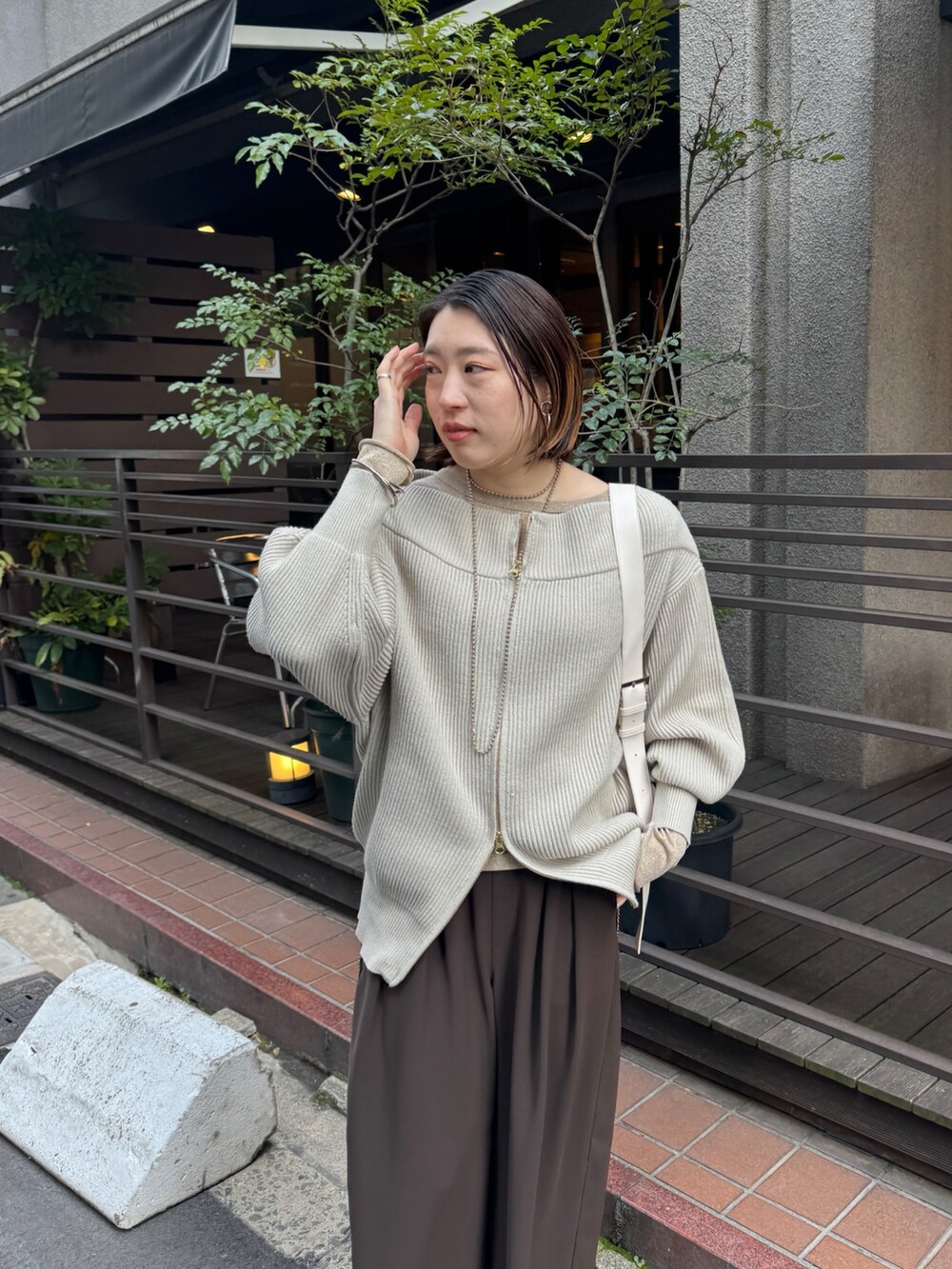 グレー系のニット/セーター、ブラウン系のスラックス、ゴールド系のTシャツ/カットソーを着用したレディースの冬コーディネートの5枚目の写真