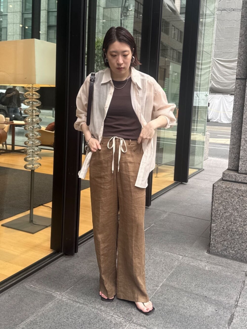 ブラウン系のショルダーバッグ、ブラウン系のTシャツ/カットソー、ベージュ系のシャツ/ブラウスを着用したレディースの夏コーディネートの8枚目の写真