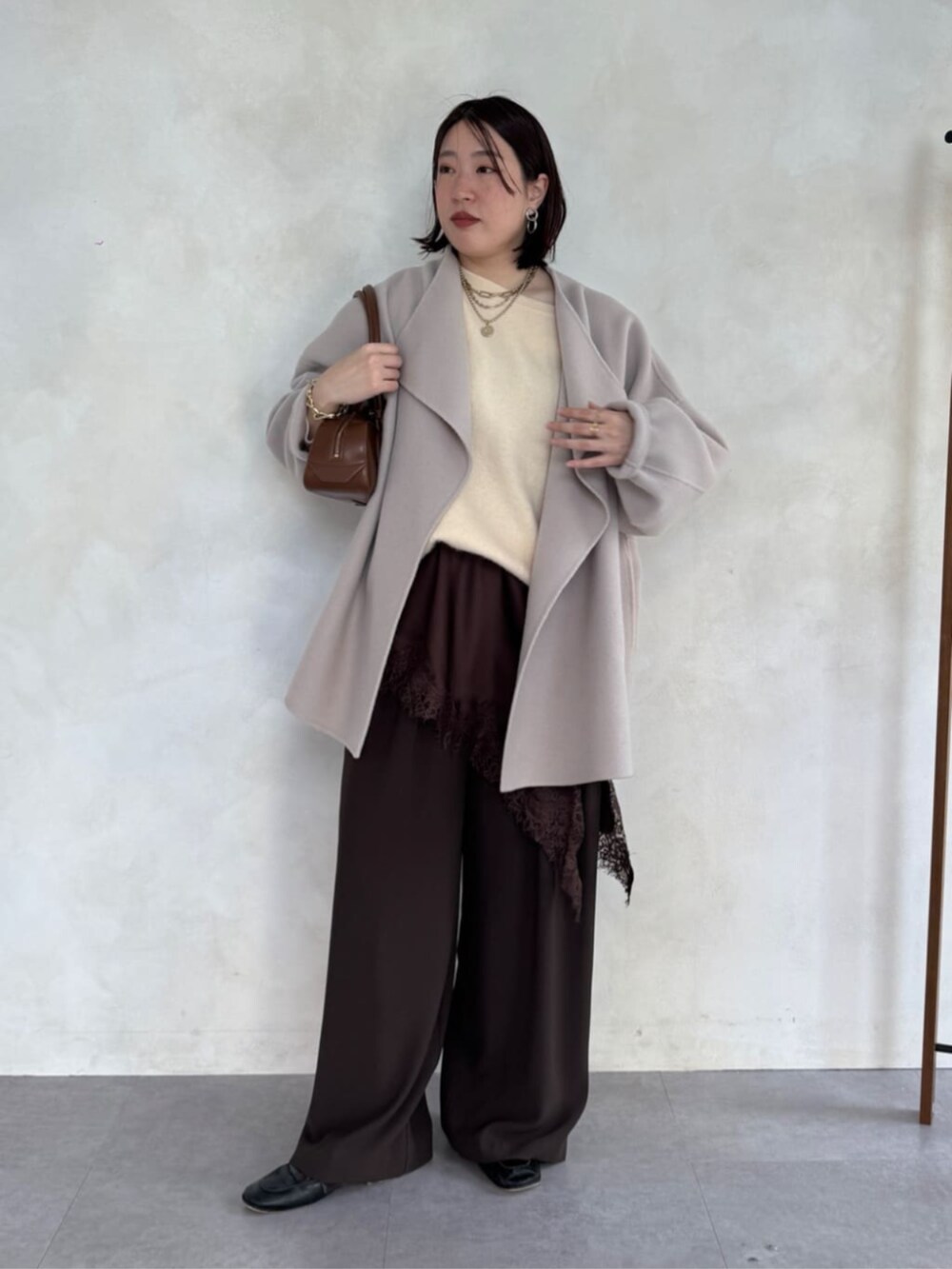 ブラウン系のスラックス、ベージュ系のその他アウター、ブラウン系のキャミソールを着用したレディースの冬コーディネートの2枚目の写真