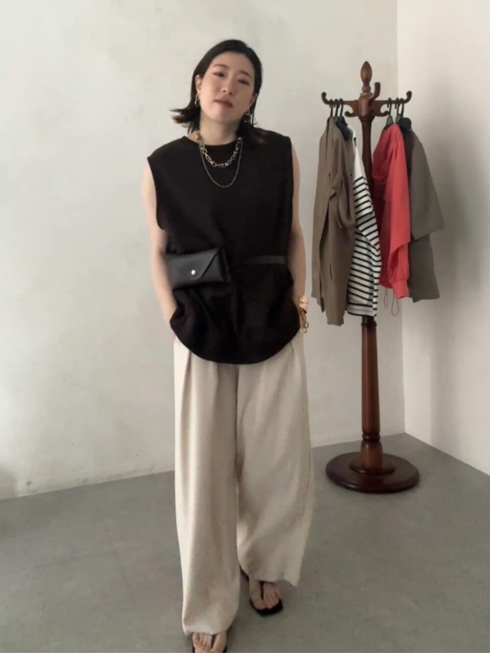 ブラウン系のショルダーバッグ、ブラウン系のTシャツ/カットソー、ベージュ系のスラックスを着用したレディースの夏コーディネートの2枚目の写真