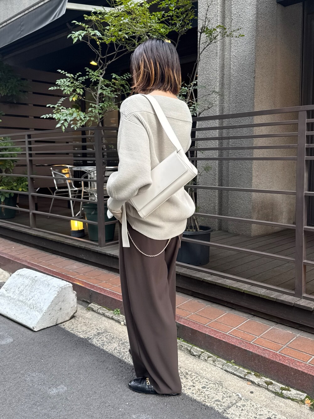 グレー系のニット/セーター、ブラウン系のスラックス、ゴールド系のTシャツ/カットソーを着用したレディースの冬コーディネートの4枚目の写真