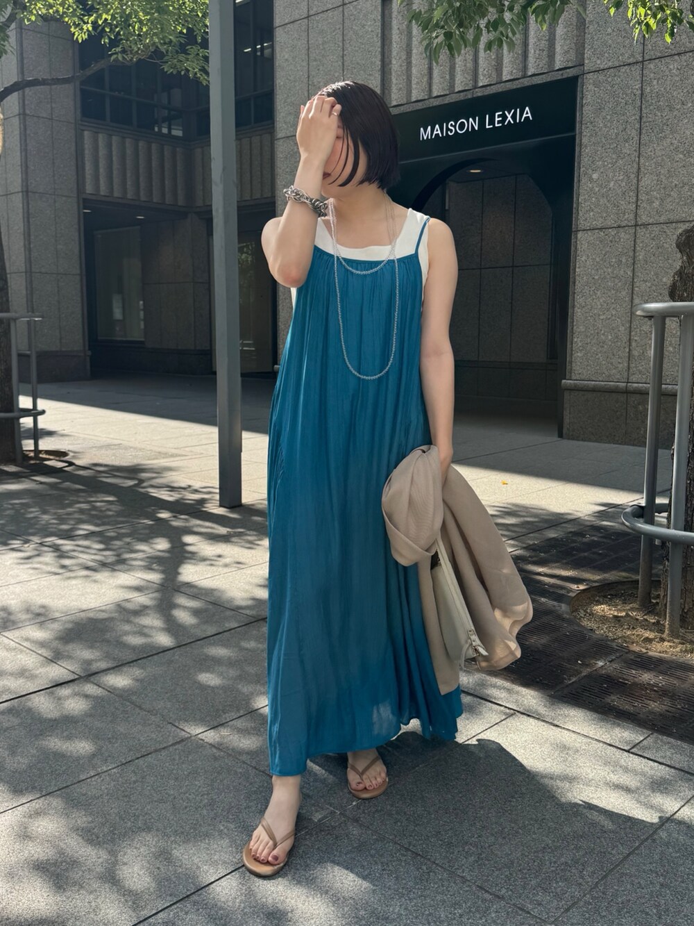 ベージュ系のテーラードジャケット、ホワイト系のタンクトップ、ブルー系のワンピースを着用したレディースの夏コーディネートの7枚目の写真