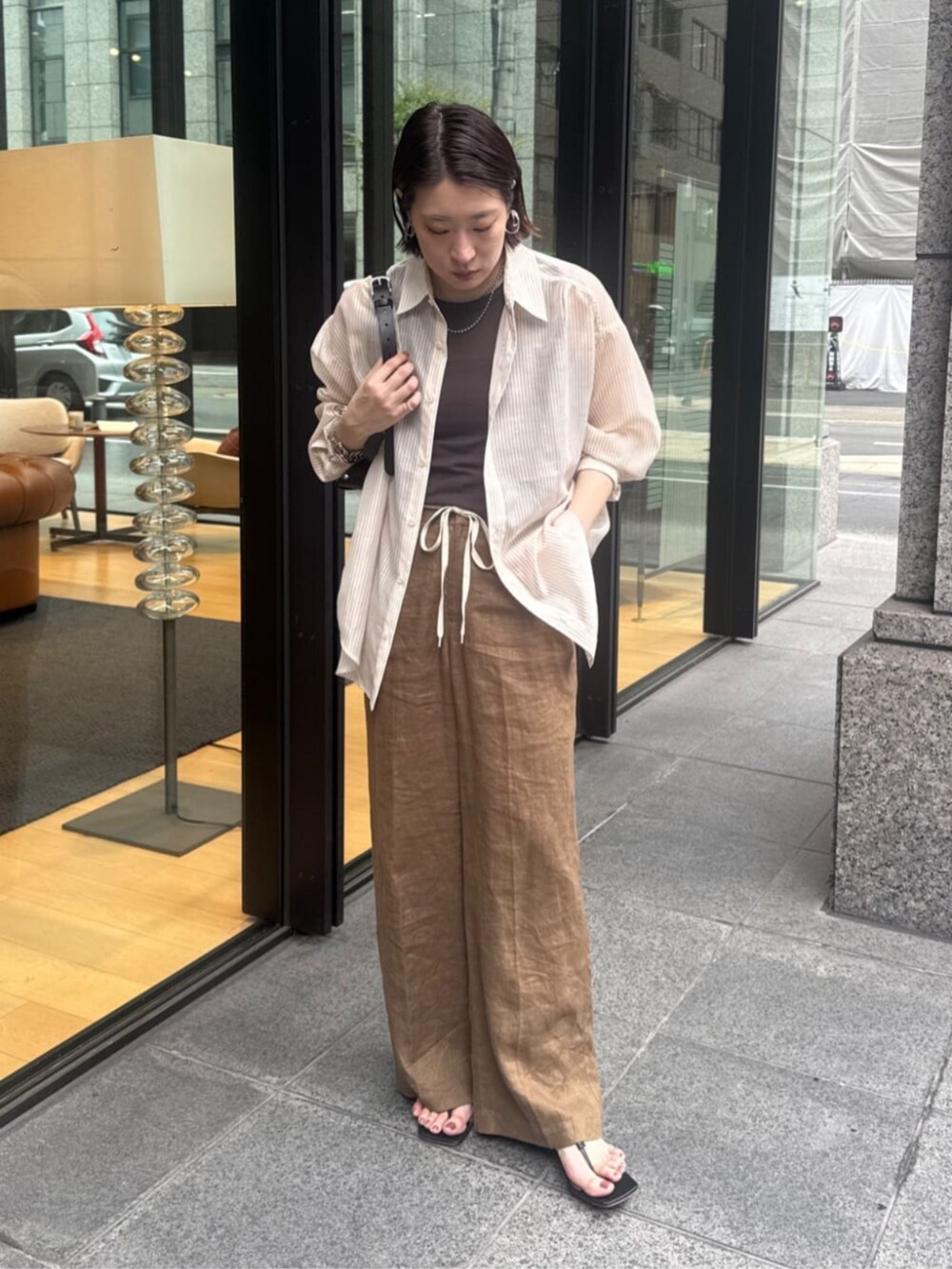 ブラウン系のショルダーバッグ、ブラウン系のTシャツ/カットソー、ベージュ系のシャツ/ブラウスを着用したレディースの夏コーディネートの6枚目の写真