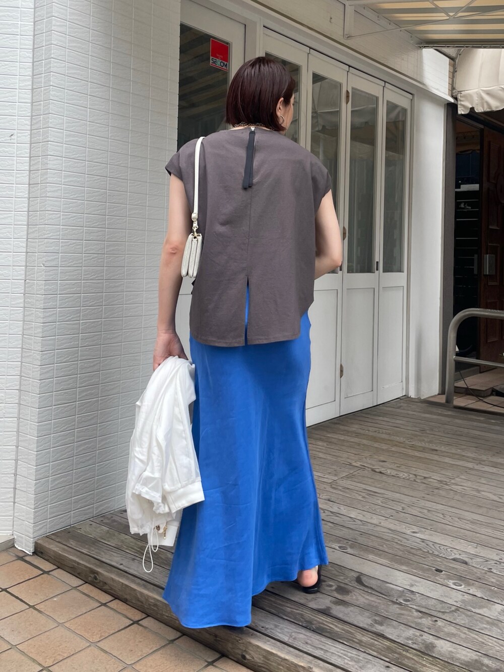 ブルー系のスカート、グレー系のTシャツ/カットソー、ホワイト系のブルゾンを着用したレディースの春コーディネートの9枚目の写真