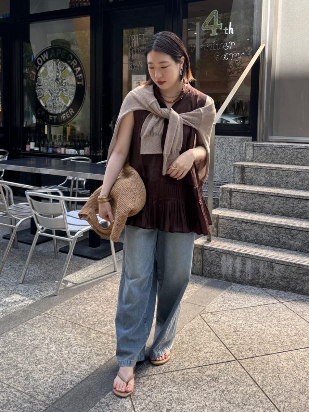 ブルー系のデニムパンツ、ベージュ系のカーディガン/ボレロ、ブラウン系のシャツ/ブラウスを着用したレディースの春コーディネートの3枚目の写真