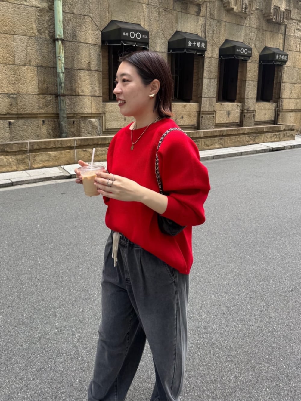 ブラック系のデニムパンツ、ブラウン系のショルダーバッグ、レッド系のニット/セーターを着用したレディースの夏コーディネートの7枚目の写真