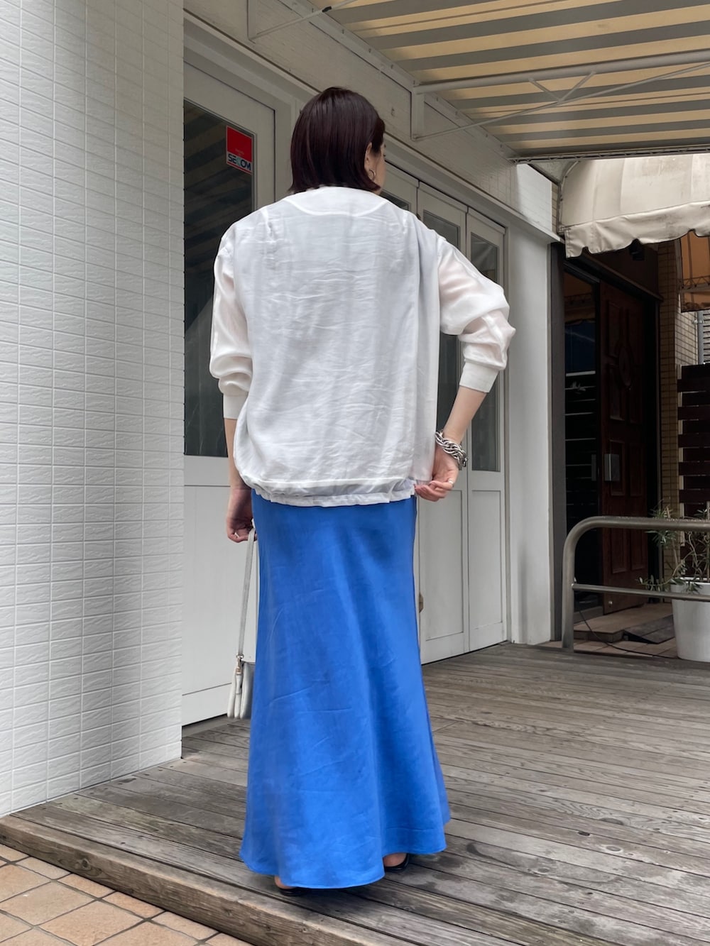 ブルー系のスカート、グレー系のTシャツ/カットソー、ホワイト系のブルゾンを着用したレディースの春コーディネートの5枚目の写真