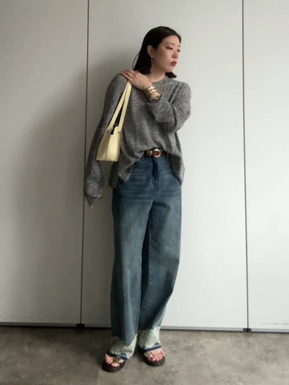 ブラック系のニット/セーター、イエロー系のショルダーバッグ、ブルー系のデニムパンツを着用したレディースの夏コーディネートの4枚目の写真