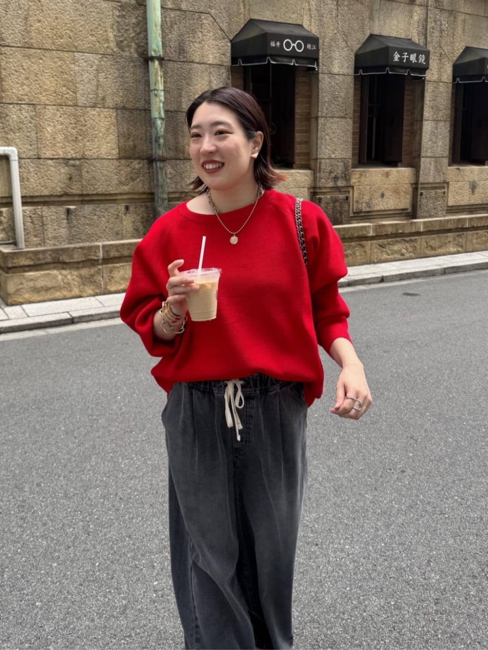 ブラック系のデニムパンツ、ブラウン系のショルダーバッグ、レッド系のニット/セーターを着用したレディースの夏コーディネートの6枚目の写真