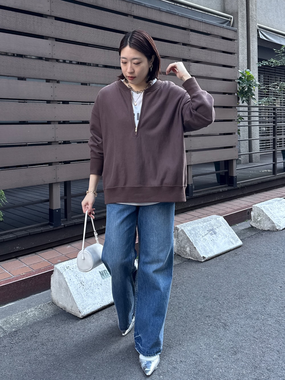 ブラウン系のスウェット、グレー系のシャツ/ブラウス、ブルー系のデニムパンツを着用したレディースの冬コーディネートの3枚目の写真