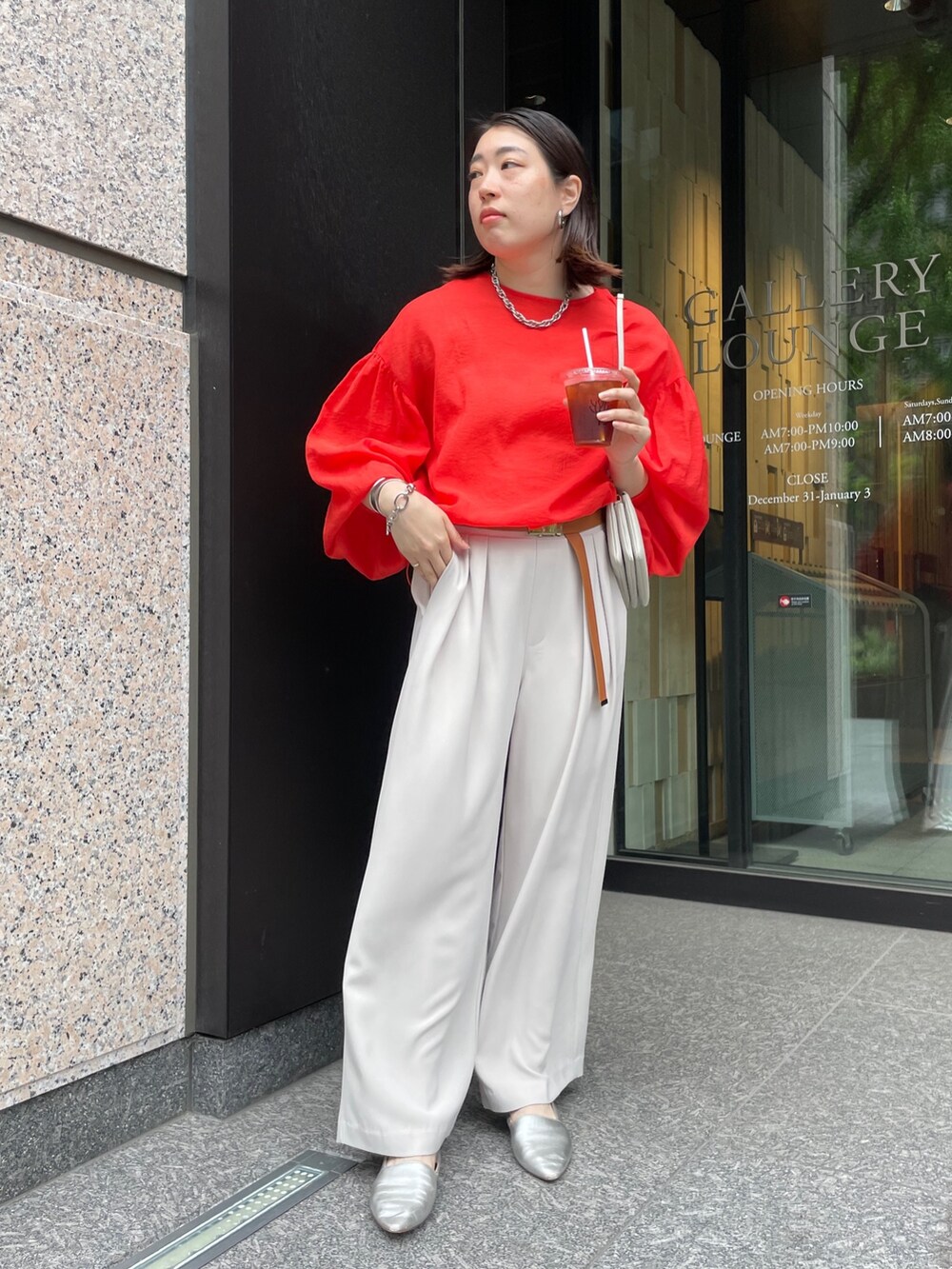 グレー系のスラックス、オレンジ系のシャツ/ブラウス、ホワイト系のショルダーバッグを着用したレディースの春コーディネートの5枚目の写真