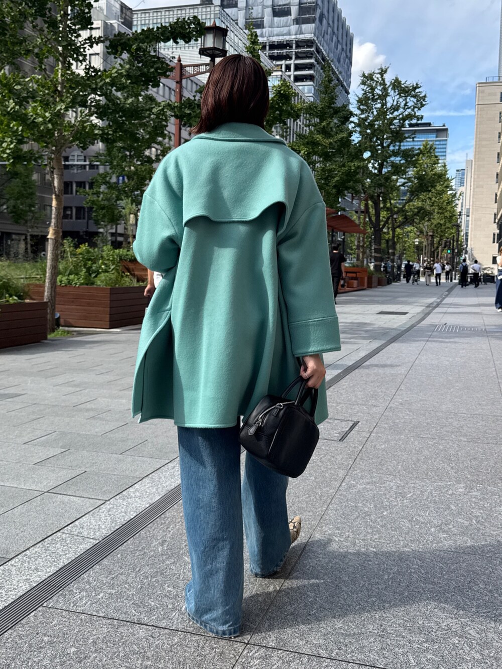 ベージュ系のニット/セーター、グリーン系のその他アウター、ブルー系のデニムパンツを着用したレディースの秋コーディネートの4枚目の写真