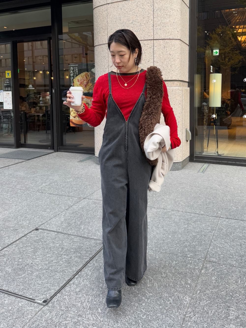 ブラック系のつなぎ/オールインワン、レッド系のニット/セーター、ブラック系のその他アウターを着用したレディースの冬コーディネートの7枚目の写真