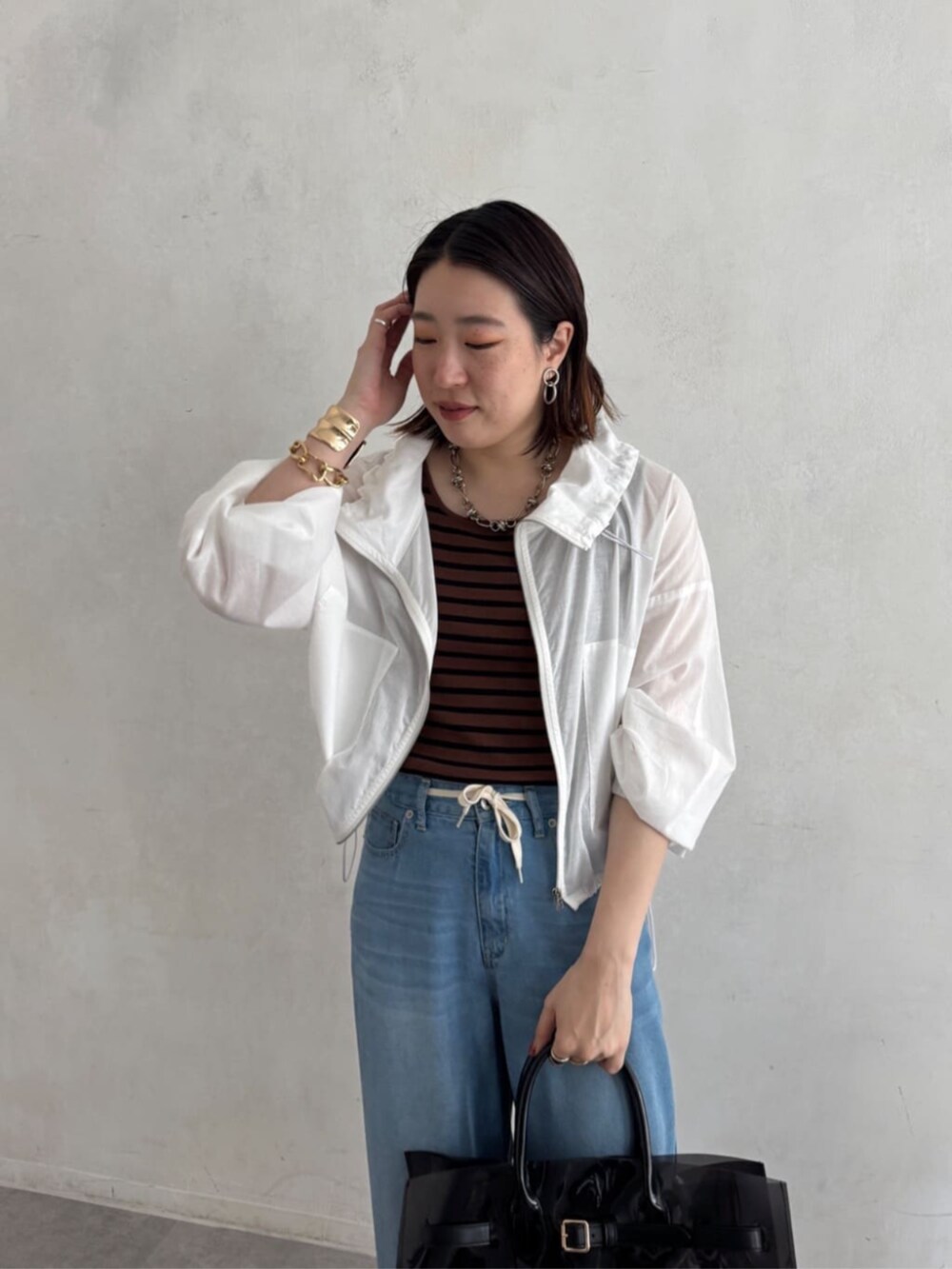 ブラック系のショルダーバッグ、ブルー系のデニムパンツ、ブラウン系のニット/セーターを着用したレディースの夏コーディネートの9枚目の写真