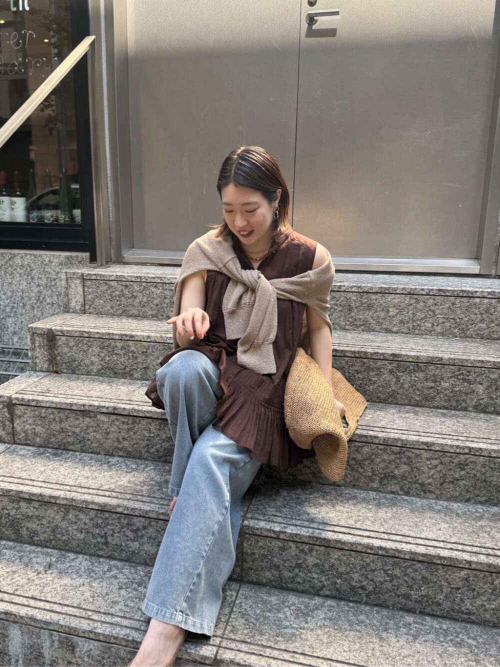 ブルー系のデニムパンツ、ベージュ系のカーディガン/ボレロ、ブラウン系のシャツ/ブラウスを着用したレディースの春コーディネートの7枚目の写真