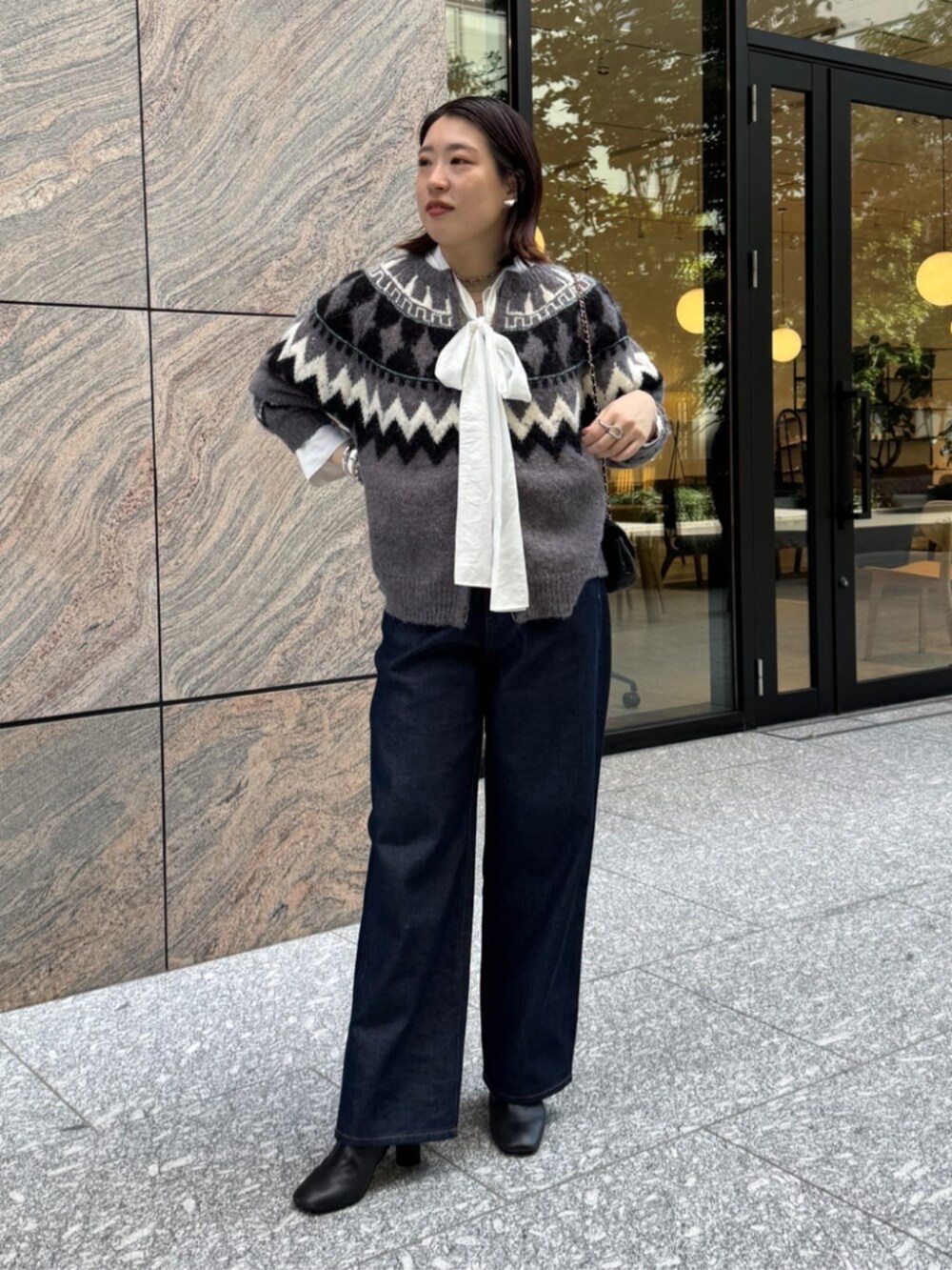 ブラック系のショルダーバッグ、ブルー系のデニムパンツ、ホワイト系のシャツ/ブラウスを着用したレディースの秋コーディネートの6枚目の写真