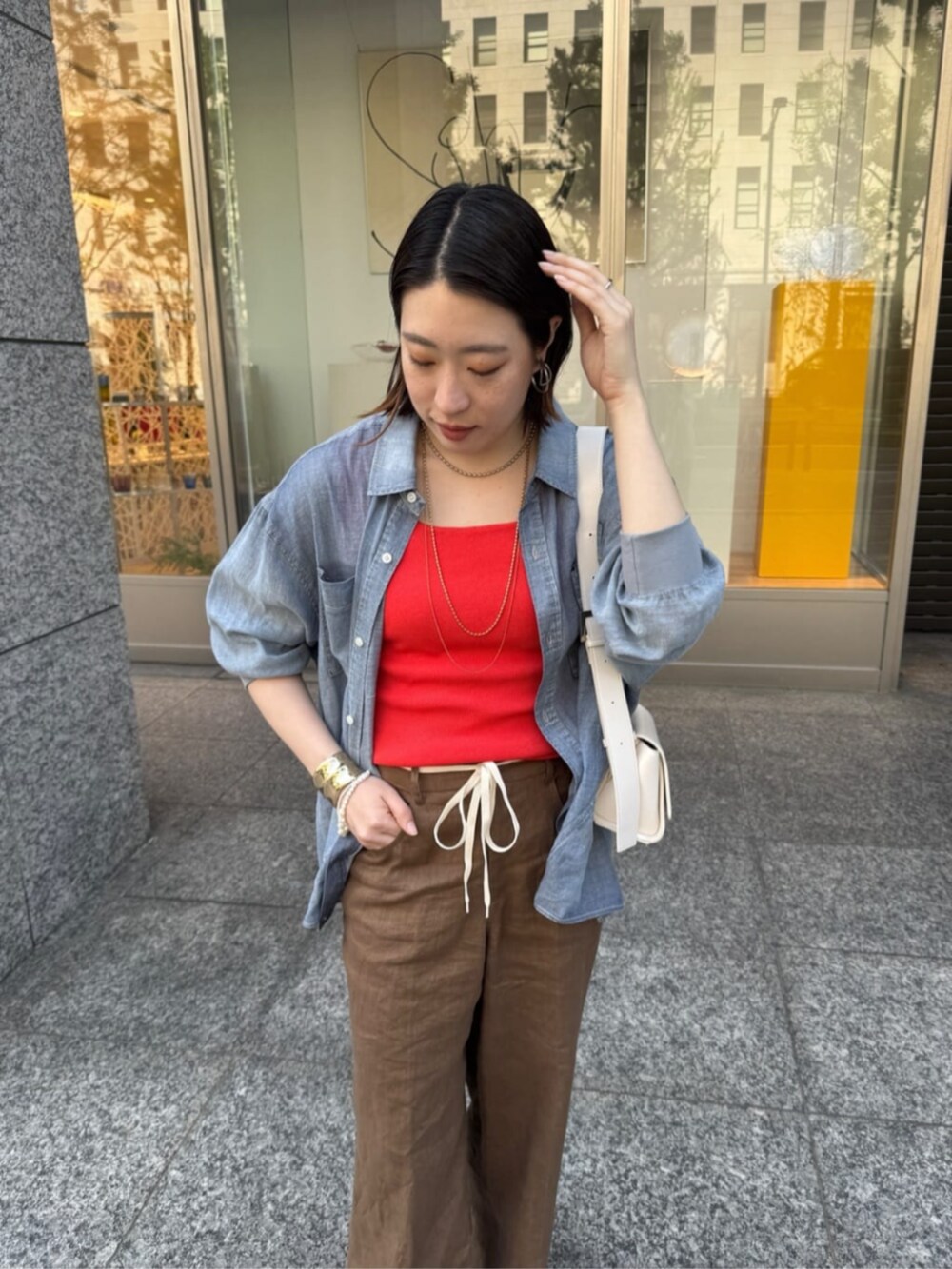 ホワイト系のショルダーバッグ、ブルー系のシャツ/ブラウス、オレンジ系のタンクトップを着用したレディースの春コーディネートの4枚目の写真