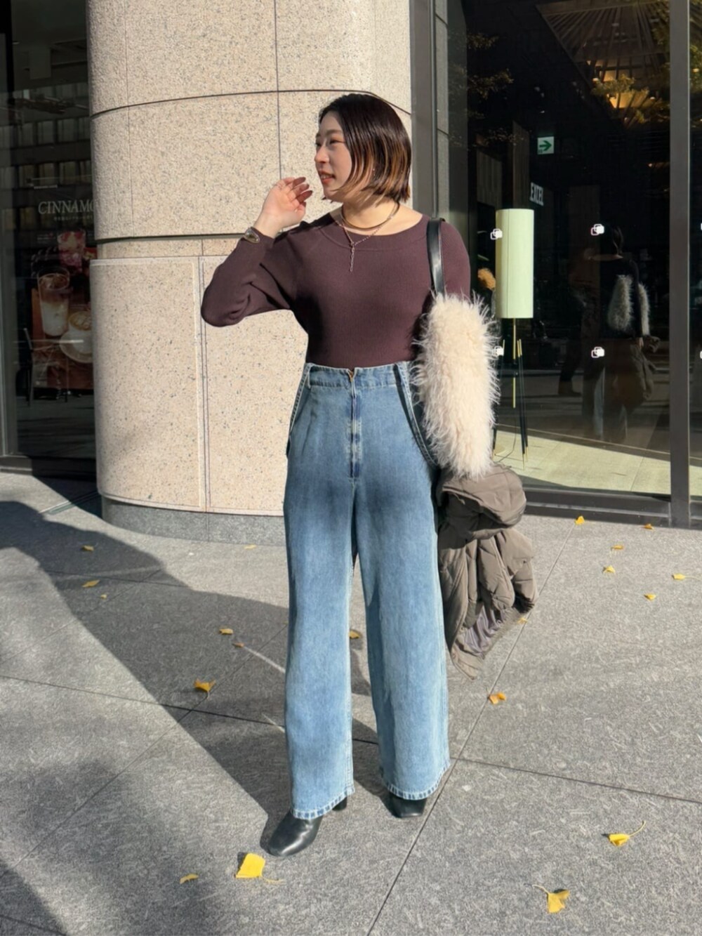 ホワイト系のショルダーバッグ、ブルー系のデニムパンツ、グレー系のその他アウターを着用したレディースの冬コーディネートの3枚目の写真