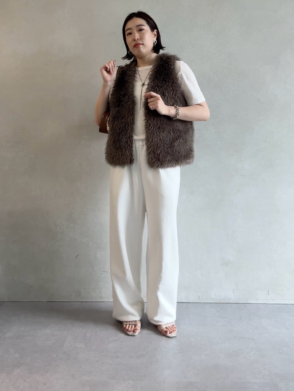 ホワイト系のスウェットパンツ、グレー系のベスト、ブラウン系のショルダーバッグを着用したレディースの秋コーディネートの5枚目の写真