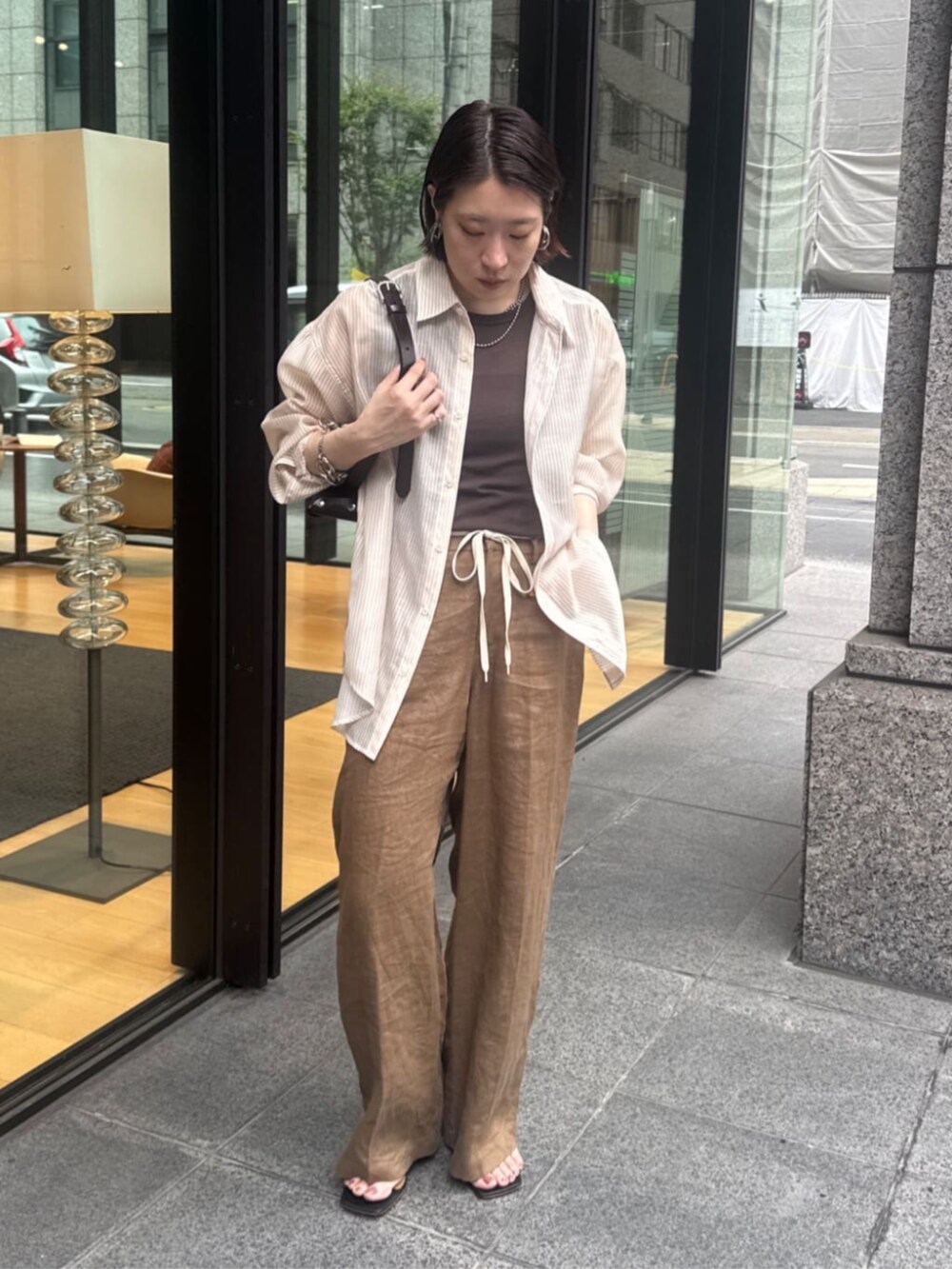 ブラウン系のショルダーバッグ、ブラウン系のTシャツ/カットソー、ベージュ系のシャツ/ブラウスを着用したレディースの夏コーディネートの5枚目の写真