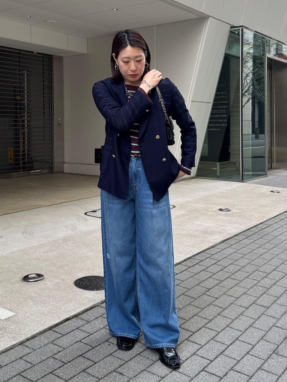 ブルー系のデニムパンツ、ブルー系のテーラードジャケット、ブラウン系のTシャツ/カットソーを着用したレディースの春コーディネートの3枚目の写真