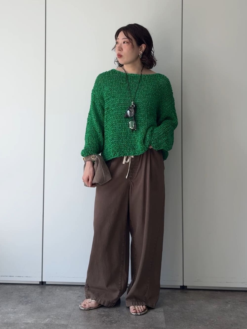 グリーン系のニット/セーター、ブラウン系のデニムパンツ、ブラウン系のネックレスを着用したレディースの秋コーディネートの2枚目の写真