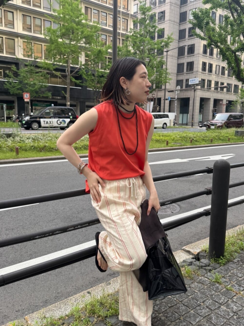 ブラック系のショルダーバッグ、オレンジ系のTシャツ/カットソー、ベージュ系のその他パンツを着用したレディースの夏コーディネートの7枚目の写真