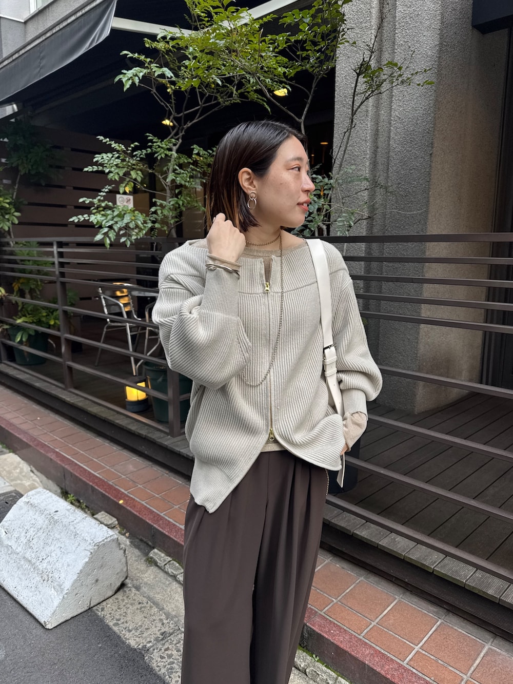 グレー系のニット/セーター、ブラウン系のスラックス、ゴールド系のTシャツ/カットソーを着用したレディースの冬コーディネートの8枚目の写真