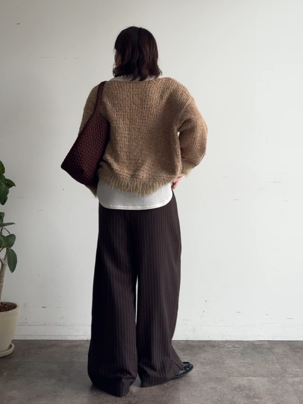 イエロー系のニット/セーター、ブラウン系のスラックス、ホワイト系のTシャツ/カットソーを着用したレディースの秋コーディネートの3枚目の写真