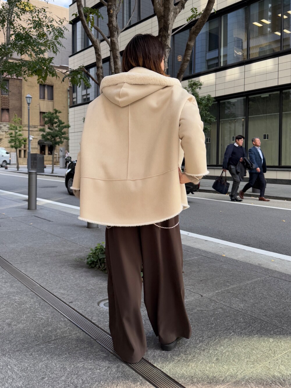 ブラウン系のスラックス、ブラウン系のニット/セーター、ホワイト系のその他アウターを着用したレディースの冬コーディネートの3枚目の写真