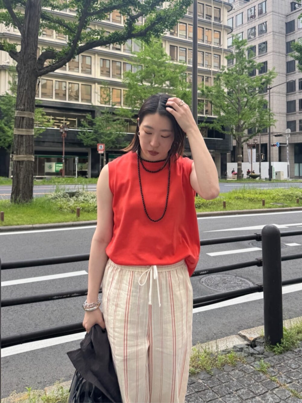 ブラック系のショルダーバッグ、オレンジ系のTシャツ/カットソー、ベージュ系のその他パンツを着用したレディースの夏コーディネートの6枚目の写真