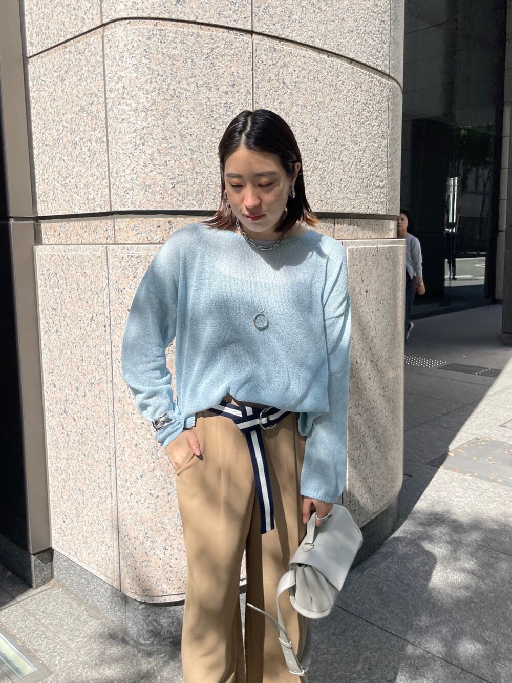 グレー系のスラックス、ブルー系のニット/セーター、ブルー系のベルトを着用したレディースの春コーディネートの8枚目の写真